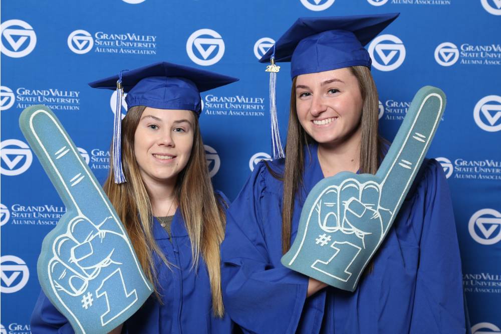 Two graduates pose with props at Gradfest